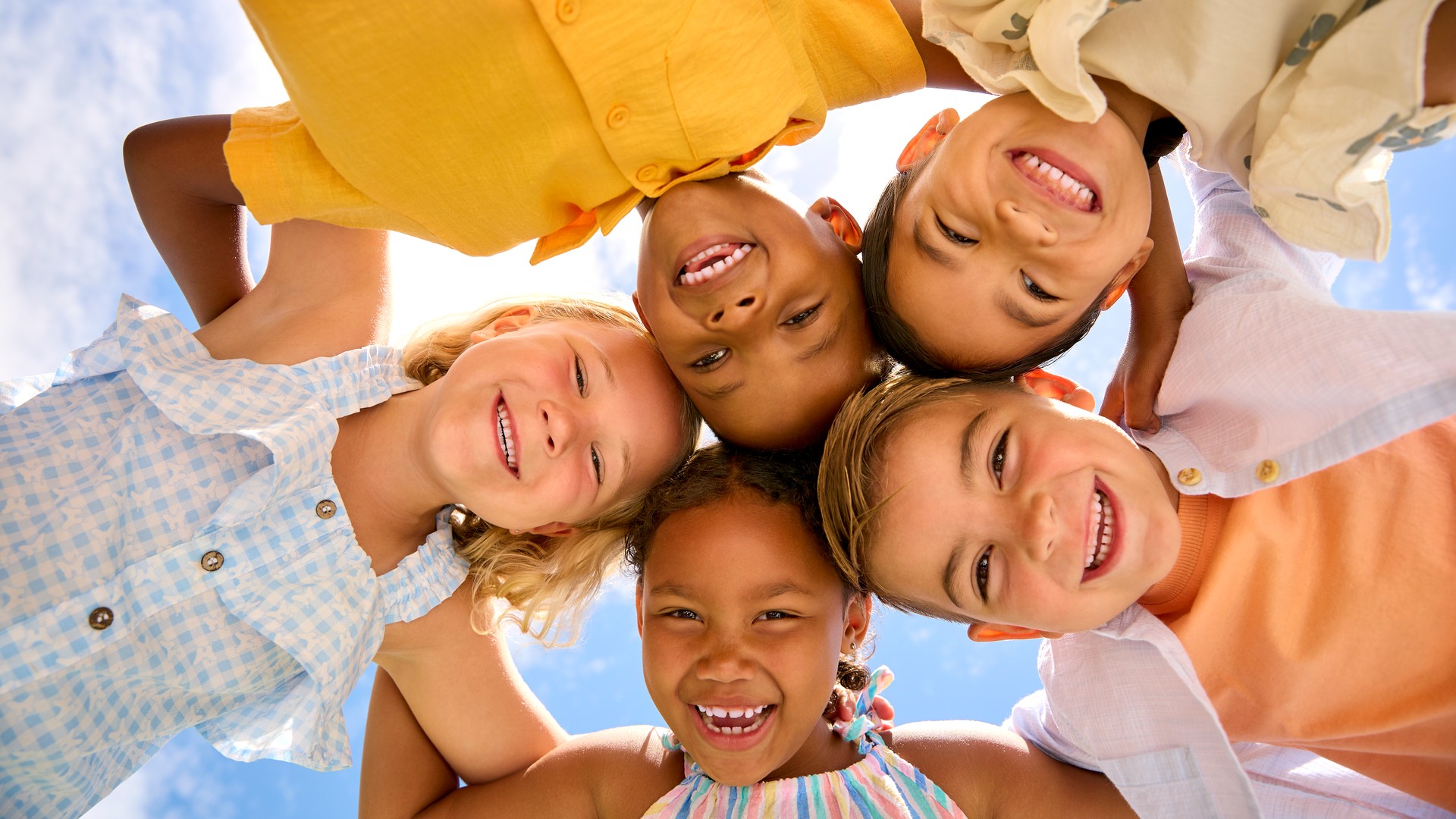 Group Of Multi-Cultural Children Friends Linking Arms Looking Down Into Camera